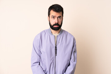 Caucasian man with beard wearing a jacket over isolated background with sad expression