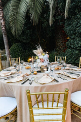 White color wedding table decorated with decorative and elegant for wedding. There are flowers, candles and serving plates on the wedding table.