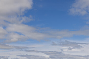 A serene blue sky canvas, adorned with gentle wisps and patches of white clouds, extending into the...