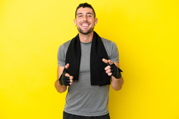 Young sport caucasian man isolated on yellow background pointing to the front and smiling