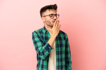 Obraz premium Young caucasian man isolated on pink background yawning and covering wide open mouth with hand