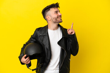 Young caucasian man with a motorcycle helmet isolated on yellow background pointing up a great idea