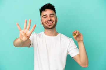 Young man holding a Bitcoin isolated on blue background happy and counting four with fingers