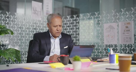 Indian Asian Hindu busy audit old aged boss man sitting chair use tablet look cam talk online video call indoor job office day gen x older elder male worker work touch pad check bank data loan