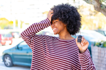 African American girl holding car keys at outdoors has realized something and intending the solution - obrazy, fototapety, plakaty