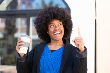African American girl holding a take away coffee at outdoors intending to realizes the solution while lifting a finger up - obrazy, fototapety, plakaty