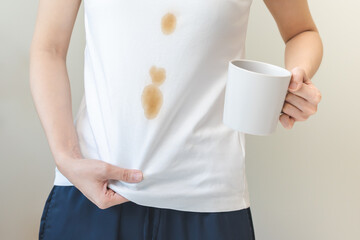 Cloth stain, disappointment asian young woman clumsy with hot coffee, tea stains on shirt, hand...