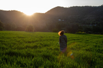 Woman with long coat holding enjoying sunset on the green meadow