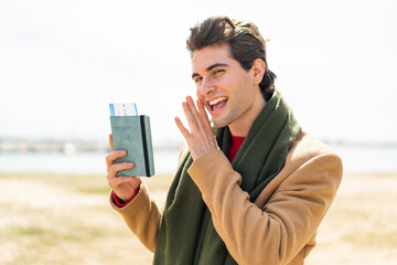 Young handsome man holding a passport at outdoors whispering something