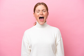 Young caucasian woman isolated on pink background shouting to the front with mouth wide open