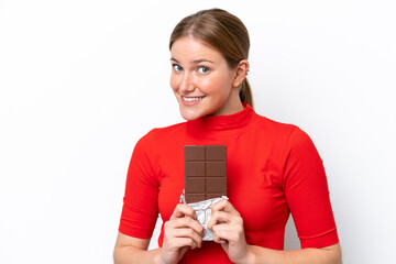 Young caucasian woman isolated on white background taking a chocolate tablet and happy