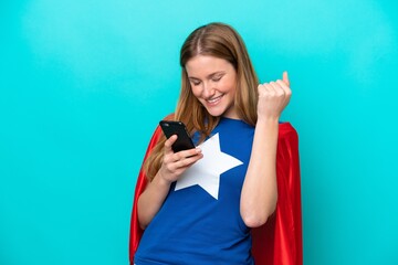 Super Hero caucasian woman isolated on blue background with phone in victory position