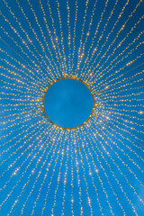 Glowing electric garland on blue sky background. Festive street decoration