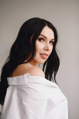 Portrait of attractive brunette woman in white shirt posing in the studio. Beautiful makeup