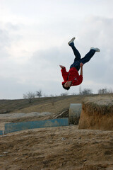 A guy does an acrobatic stunt on a sea sandy beach against a background of a cloudy gray sky	
