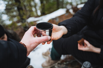 A man passes a glass of tea to a woman, a cup of coffee in the hands of a man, a metal cup for hot...