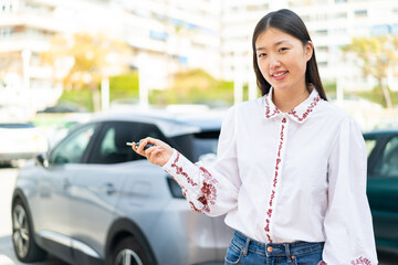 Young Chinese woman at outdoors holding car keys with happy expression