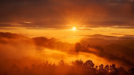 Naklejka na ściany i meble The sun is setting over a foggy mountain range