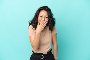 Young asian woman isolated on blue background happy and smiling covering mouth with hand