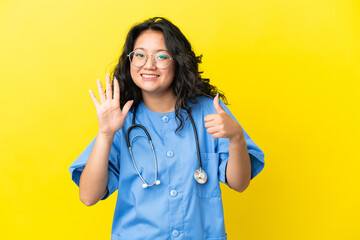 Young surgeon doctor asian woman isolated on yellow background counting six with fingers