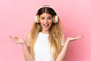 Young blonde woman isolated on blue background surprised and listening music