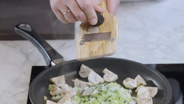 Traditional French and Italian cuisine. Chef grating black truffle on slices in a pan to prepare the white sauce for the pasta. Food preparation. Slow motion 100fps,, 4k