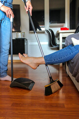 Man sweeping the living room dream under the feet of woman with baby, vertical, unrecognizable,...
