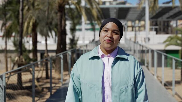 Muslim modern girl walking in the street. Arab young woman in the park smiling.
