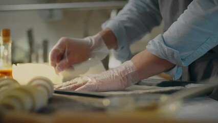 Kitchen. A pastry chef dressed in a modern uniform places parchment on a baking sheet in a bakery workshop. A modern man prepares a baking tray in the oven, masters new baking recipes, product