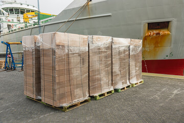 stacks of packed new cardboard boxes stand outside on the harbor quay