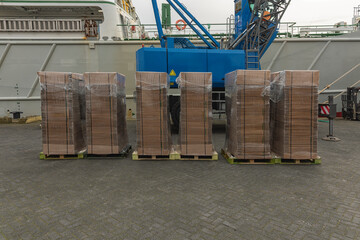 stacks of packed new cardboard boxes stand outside on the harbor quay