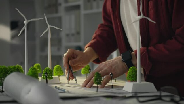 A technical engineer uses models of wind turbines. The designer develops prototypes for the placement of wind turbines to promote green energy and alternative energy sources.