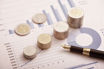 Coins and pens placed on financial data reports