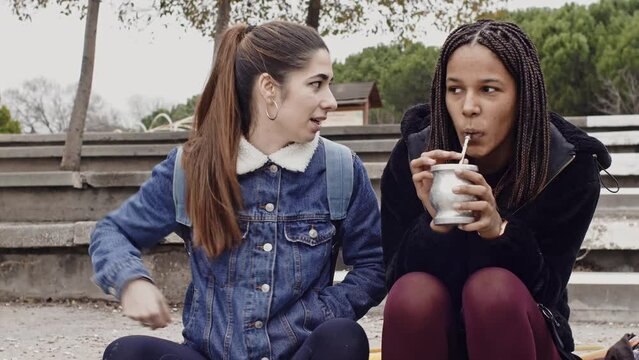 Diverse women friends relaxing together drinking mate