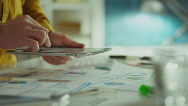 In an authentic office space, a creative employee uses a touchpad and the most advanced technology to analyze data. His ideation process is based on a deep dive into analytics