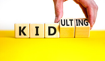 Kid or kidulting symbol. Concept words Kid or Kidulting on wooden cubes. Beautiful yellow table...