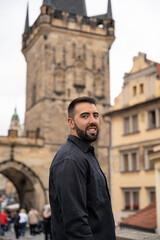 Young male tourist with beard posing on the Charles Bridge, Prague.