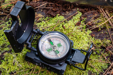 Old compass on green mossy wood. direction finder compass. Aiming compass