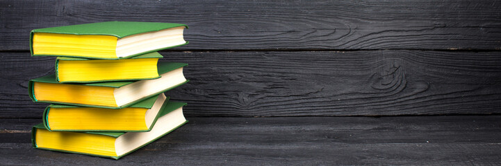 Books on wooden table, black board background. Back to school. Education business concept....