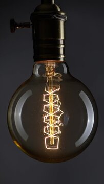 Close up shot of vintage lamp spiral blinking. Light bulb over black background. Network overload, power outage. Blackout concept. Vertical Screen