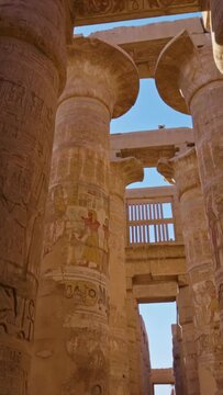 Camera moves between columns with ancient Egyptian drawings. Karnak Temple in Luxor, Egypt. Majestic columns with ancient Egyptian drawings. Vertical screen