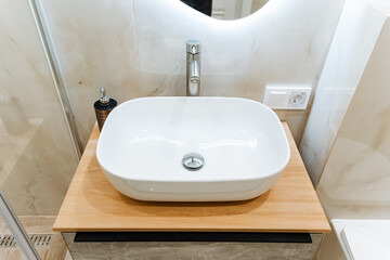 Bathroom sink atop wood counter, with plumbing fixture tap
