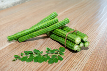 Moringa Oleifera or drumstick vegetable with leaves on wooden background