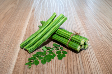 Moringa Oleifera or drumstick vegetable with leaves on wooden background