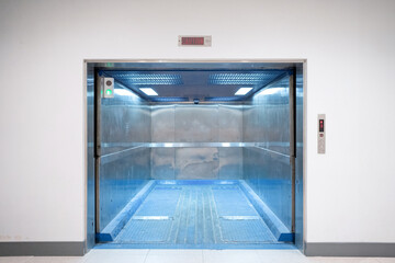 Modern freight elevator featuring a sleek two-section slide-up door design. Empty freight elevator