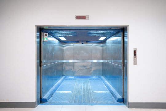Modern freight elevator featuring a sleek two-section slide-up door design. Empty freight elevator