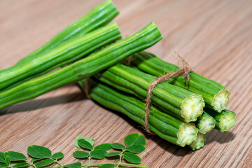 Moringa Oleifera or drumstick vegetable with leaves on wooden background