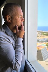 Profile of an adult man looking out the window with a sad and curious look. Depression. Family...