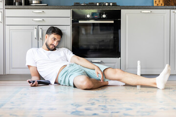 Tired man sitting on the floor after exhausted cleaning day at home