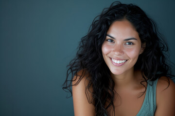 Smiling Hispanic woman with curly hair against a dark background